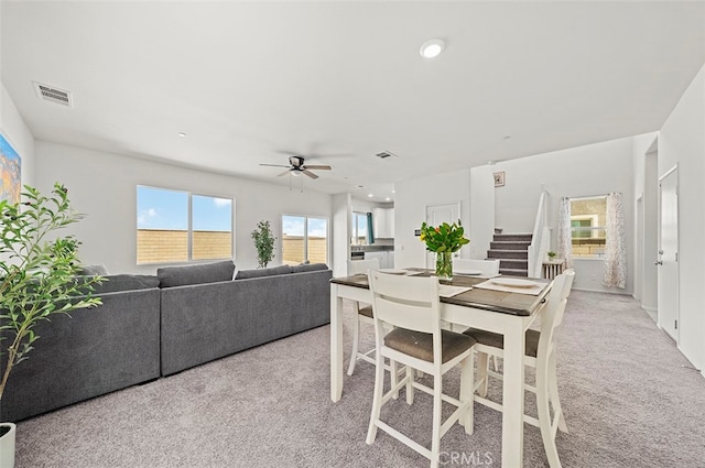 carpeted dining area with ceiling fan and plenty of natural light