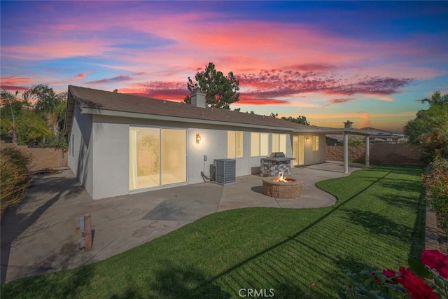 back house at dusk with a yard, a patio, central AC, and a fire pit