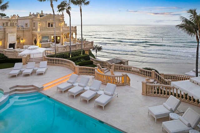 view of swimming pool with a patio area, exterior fireplace, and a water view