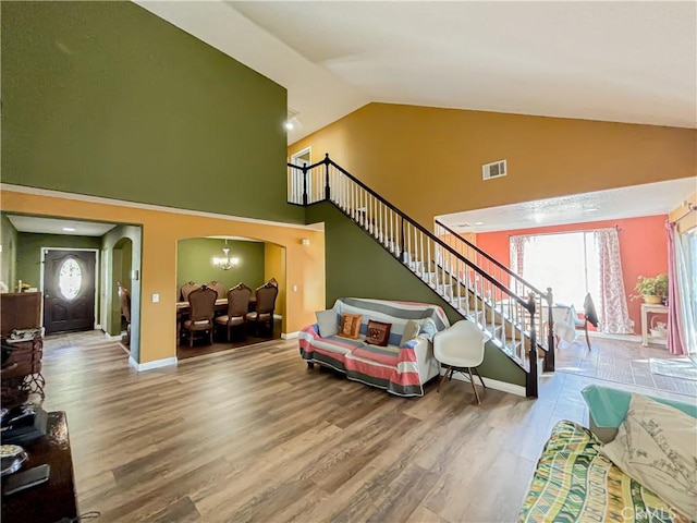 living room featuring hardwood / wood-style floors, high vaulted ceiling, and an inviting chandelier