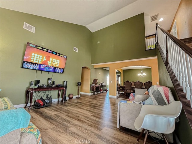 living room with high vaulted ceiling, wood-type flooring, and an inviting chandelier