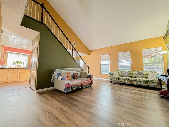 living room with hardwood / wood-style floors, a towering ceiling, and a textured ceiling