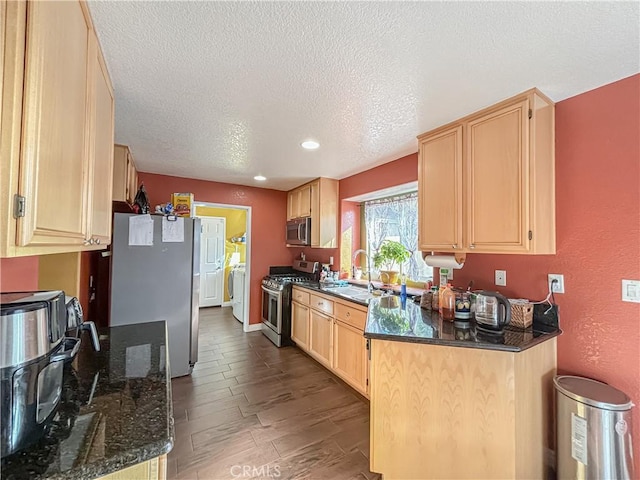 kitchen featuring light brown cabinets, hardwood / wood-style flooring, dark stone countertops, a textured ceiling, and stainless steel appliances