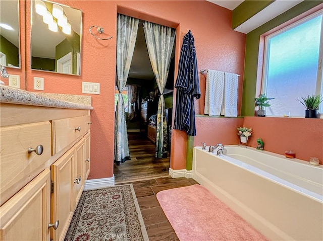 bathroom with a tub to relax in, vanity, and hardwood / wood-style flooring