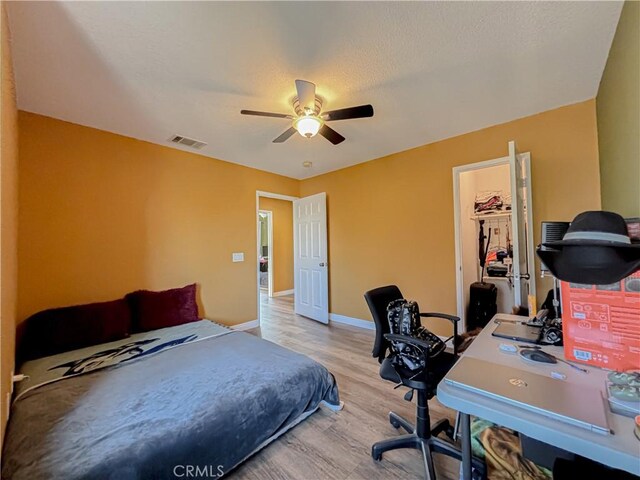 bedroom with ceiling fan, light wood-type flooring, a spacious closet, and a closet