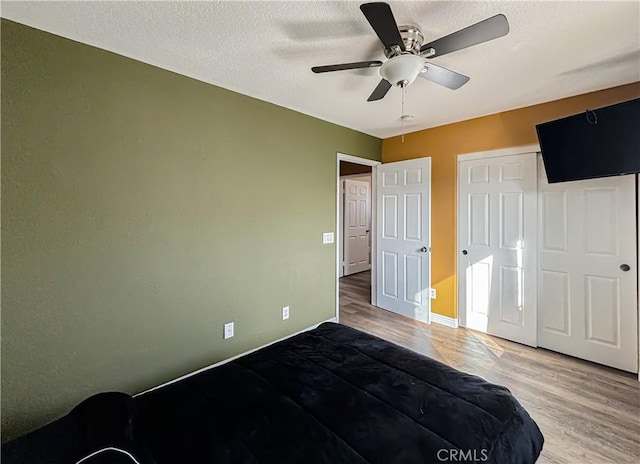 bedroom with ceiling fan, a closet, wood-type flooring, and a textured ceiling