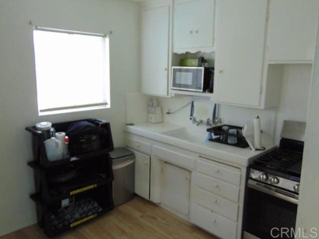 kitchen featuring white cabinets, gas stove, and light hardwood / wood-style floors