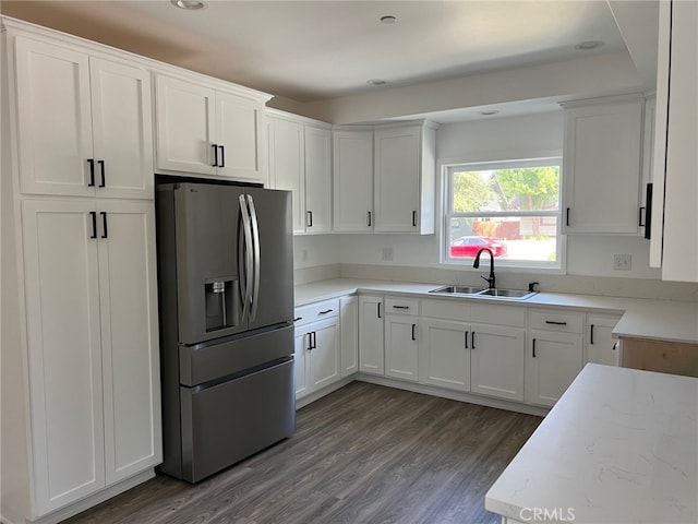 kitchen with white cabinetry, sink, light stone counters, dark hardwood / wood-style floors, and stainless steel fridge