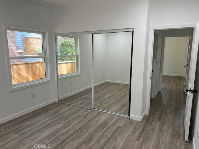 unfurnished bedroom with a closet and dark wood-type flooring