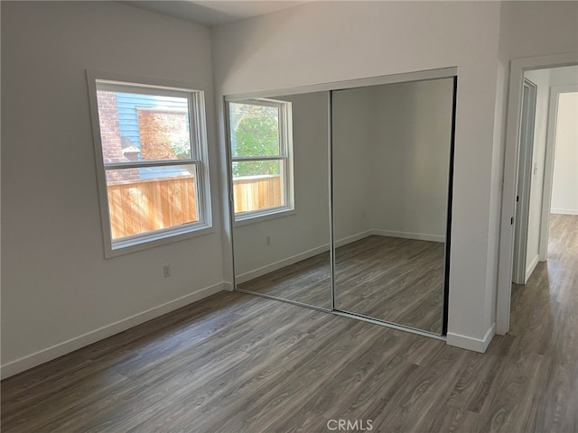 unfurnished bedroom with a closet and dark hardwood / wood-style floors