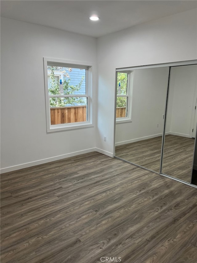 unfurnished bedroom featuring dark wood-type flooring and a closet