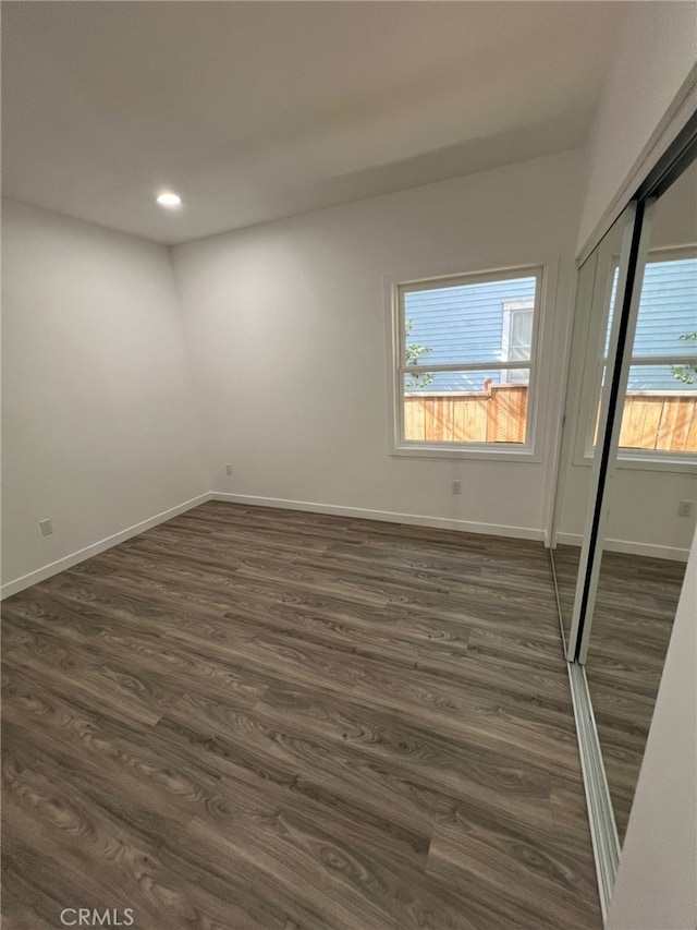 spare room with dark hardwood / wood-style flooring and plenty of natural light