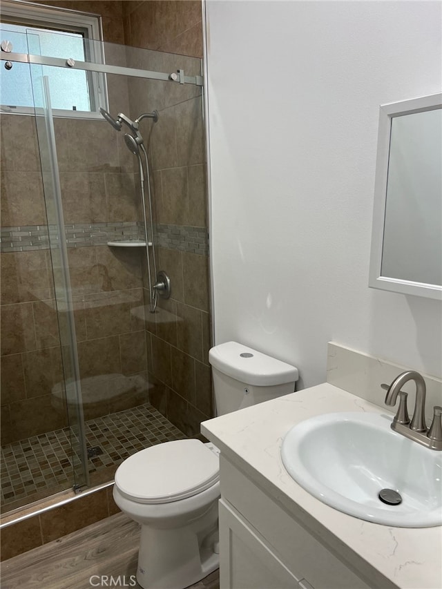 bathroom featuring hardwood / wood-style floors, vanity, toilet, and a shower with shower door