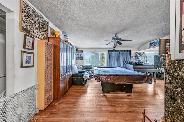 game room featuring pool table, a textured ceiling, hardwood / wood-style flooring, and ceiling fan