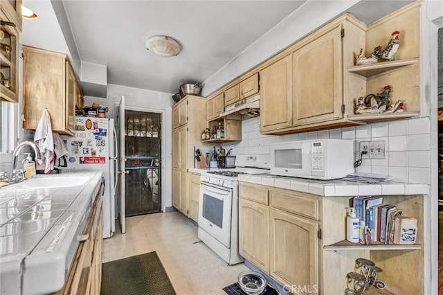 kitchen with white appliances, decorative backsplash, sink, and tile counters