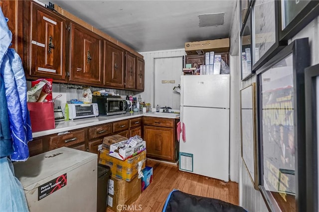 kitchen featuring white fridge, sink, and wood-type flooring