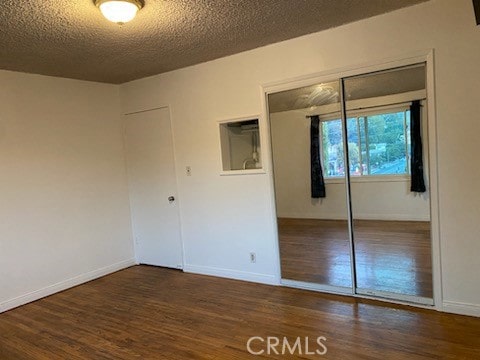 unfurnished bedroom with a closet, dark wood-type flooring, and a textured ceiling