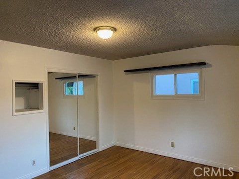 unfurnished bedroom with a closet, multiple windows, and dark hardwood / wood-style floors