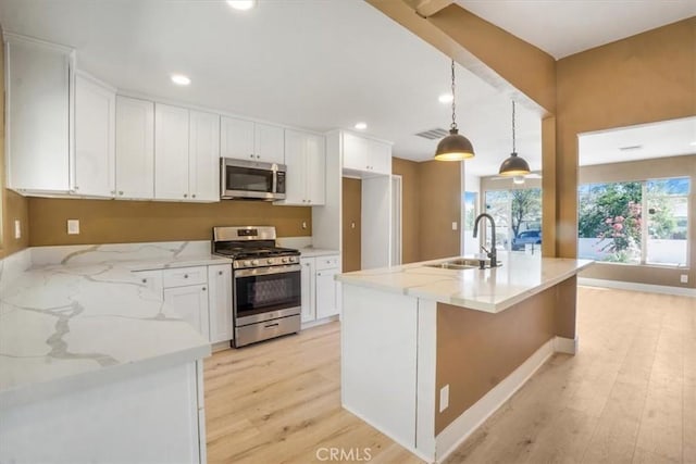 kitchen with white cabinetry, stainless steel appliances, hanging light fixtures, light stone counters, and sink