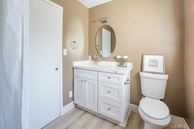 bathroom with wood-type flooring, toilet, and vanity