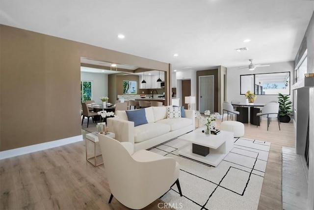 living room with sink, light hardwood / wood-style flooring, and ceiling fan