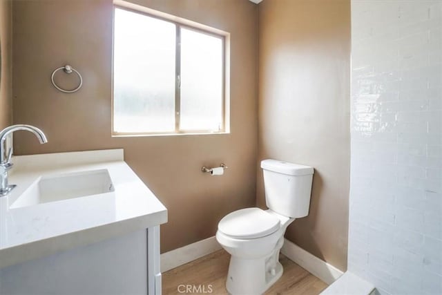 bathroom with toilet, vanity, a healthy amount of sunlight, and hardwood / wood-style flooring