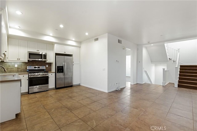 kitchen with sink, stainless steel appliances, light tile patterned floors, backsplash, and white cabinets