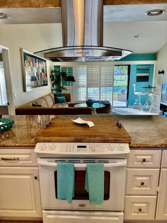 kitchen featuring white cabinetry, dark stone countertops, stove, and range hood