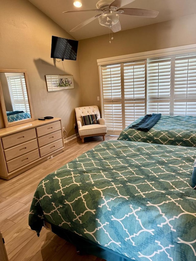 bedroom featuring ceiling fan, multiple windows, lofted ceiling, and light wood-type flooring