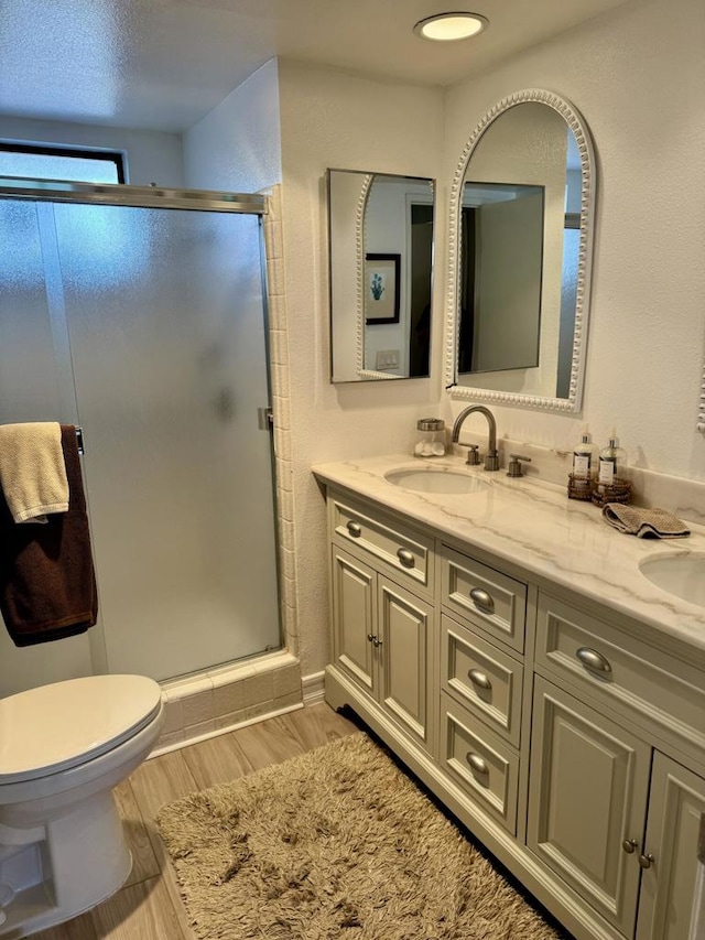 bathroom featuring wood-type flooring, an enclosed shower, vanity, and toilet