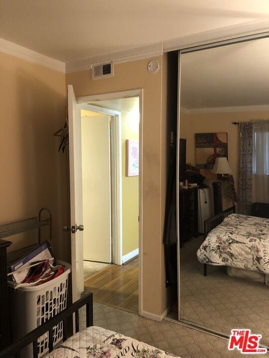 bedroom with hardwood / wood-style flooring, crown molding, and a closet