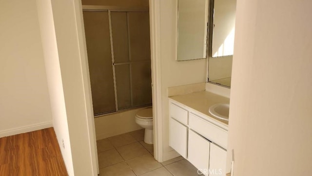 full bathroom featuring toilet, vanity, wood-type flooring, and combined bath / shower with glass door