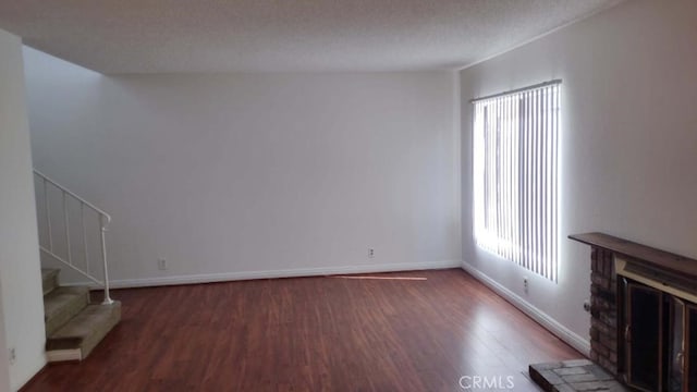 unfurnished living room featuring a textured ceiling and dark hardwood / wood-style floors