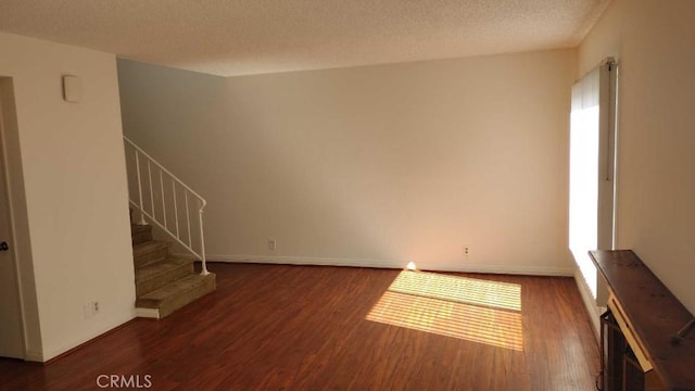 unfurnished living room featuring a textured ceiling, plenty of natural light, and dark hardwood / wood-style floors