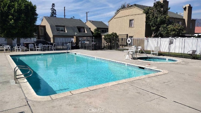 view of swimming pool featuring a hot tub and a patio area