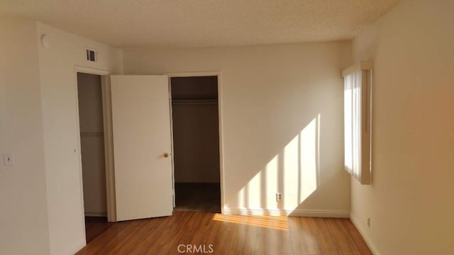 unfurnished bedroom with a closet, wood-type flooring, and a textured ceiling