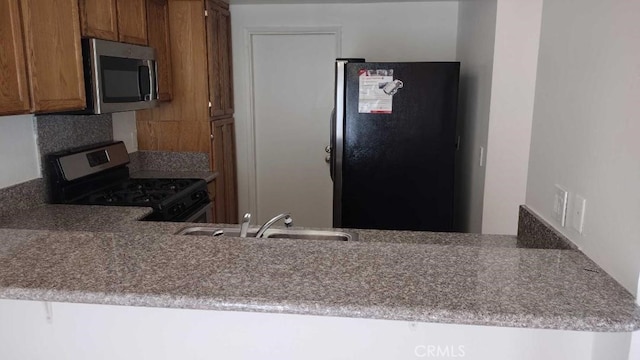 kitchen with black appliances, kitchen peninsula, and sink