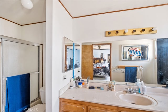 bathroom with a shower with door, vanity, crown molding, and toilet