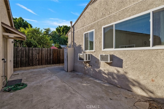 view of side of home featuring a wall unit AC and a patio area