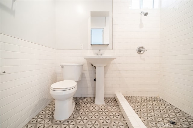 bathroom featuring tile walls, a tile shower, and toilet