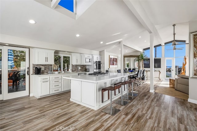 kitchen with white cabinetry, a kitchen island, vaulted ceiling with beams, and a healthy amount of sunlight