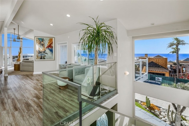 living room featuring hardwood / wood-style floors, lofted ceiling with beams, and a water view