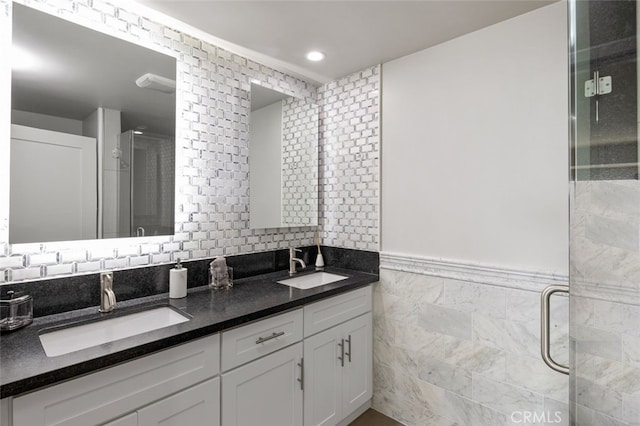 bathroom with vanity, a shower with door, and tile walls