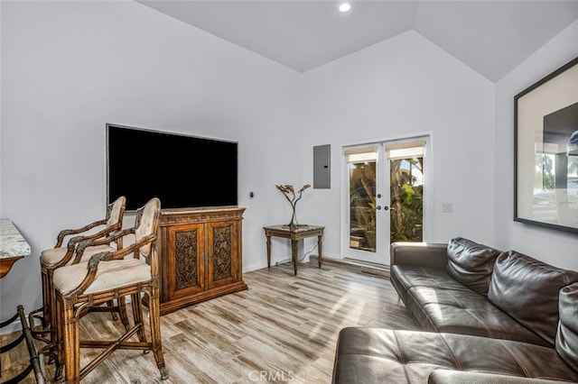 living room featuring lofted ceiling, electric panel, french doors, and light wood-type flooring