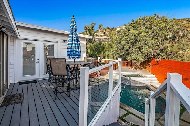 wooden deck featuring a fenced in pool, french doors, and pool water feature