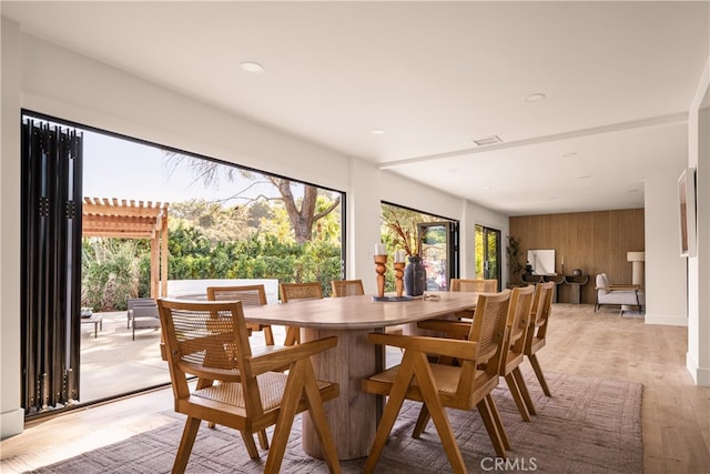 dining area featuring light hardwood / wood-style floors and wood walls