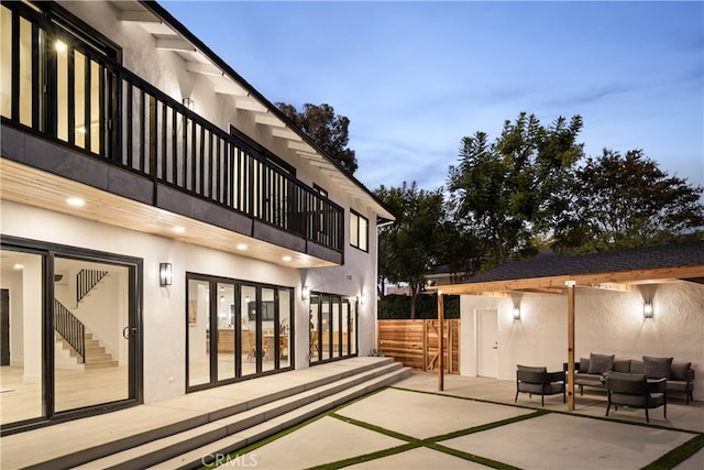 patio terrace at dusk with outdoor lounge area and a balcony