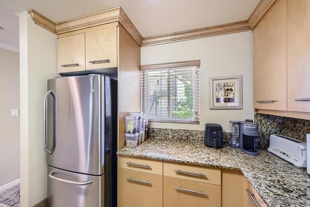 kitchen featuring light brown cabinetry, stainless steel fridge, and light stone countertops