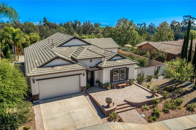 view of front of property with fence, a tiled roof, concrete driveway, stucco siding, and a garage