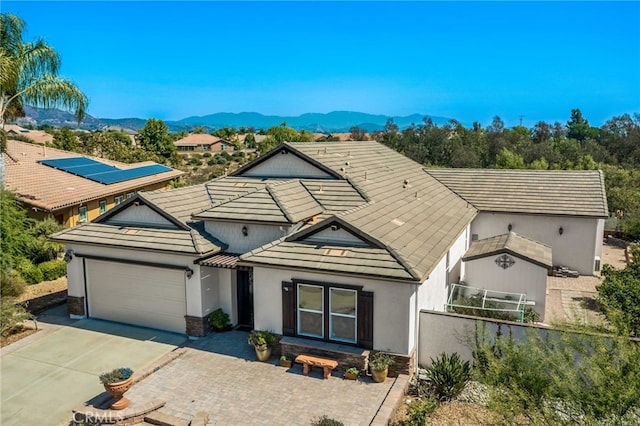 view of front of property featuring fence, driveway, an attached garage, stucco siding, and a mountain view